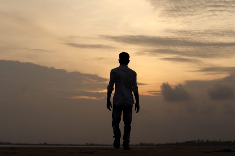A solitary silhouette of a man walking during a serene sunset in India, reflecting solitude and introspection.