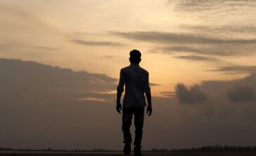 A solitary silhouette of a man walking during a serene sunset in India, reflecting solitude and introspection.